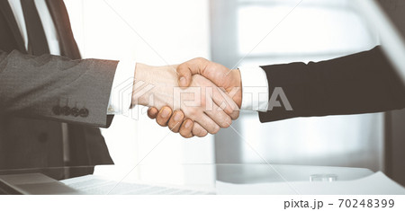 Unknown diverse business people are shaking hands finishing contract signing in sunny office, close-up. Business handshake concept Unknown diverse business people are shaking hands finishing contract signing in sunny office, close-up. Business handshake concept 70248399