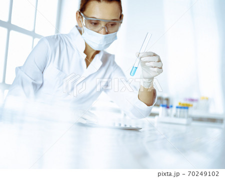 Female laboratory assistant analyzing test tube with blue liquid. Medicine, health care and researching concept 70249102