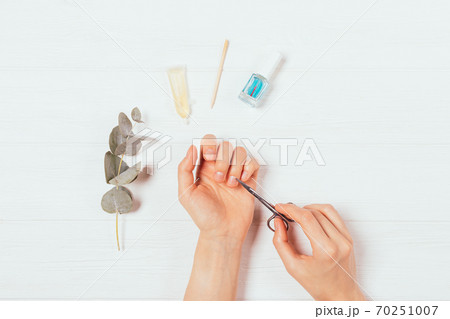 Top view of female hands doing manicure using scissors Top view of female hands doing manicure using scissors 70251007