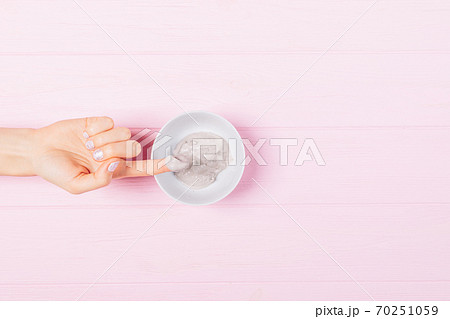 Female hand takes sample of clay facial mask from bowl Female hand takes sample of clay facial mask from bowl 70251059