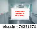 Sign on the door of a hospital corridor indicating an access area reserved for patients with covid-19 70251678