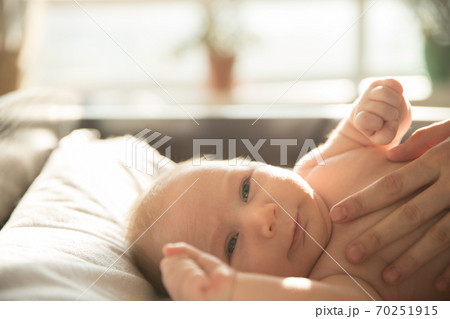 LIttle baby lying on the bed and his mother standing above with her hands on him LIttle baby lying on the bed and his mother standing above with her hands on him 70251915