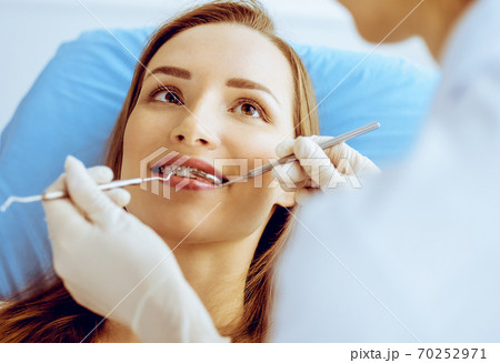 Smiling young woman with orthodontic brackets examined by dentist in dental clinic. Healthy teeth and medical care concept 70252971