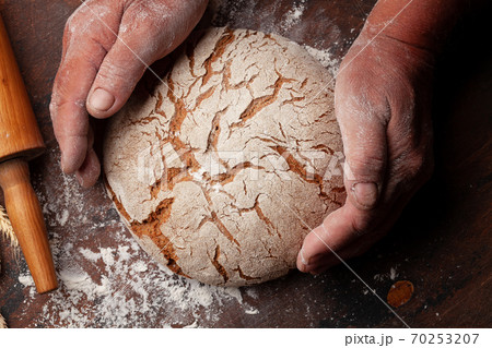 Baker holding fresh baked homemade bread Baker holding fresh baked homemade bread 70253207