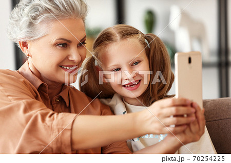 Grandmother taking selfie with granddaughter. 70254225