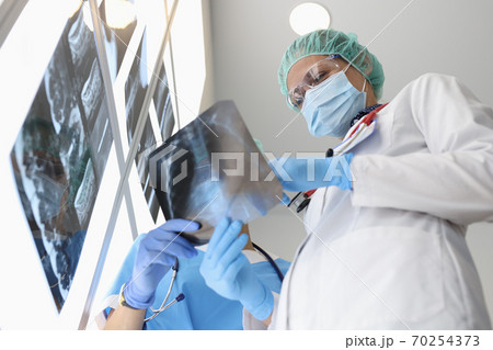 Doctors examine an X-ray when discussing it. Doctors examine an X-ray when discussing it. 70254373