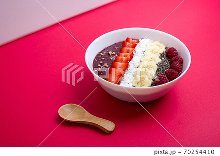Smoothie bowl or acai berry bowl with chia, strawberries, raspberries, banana slices and coconut flakes. Top view. 70254410