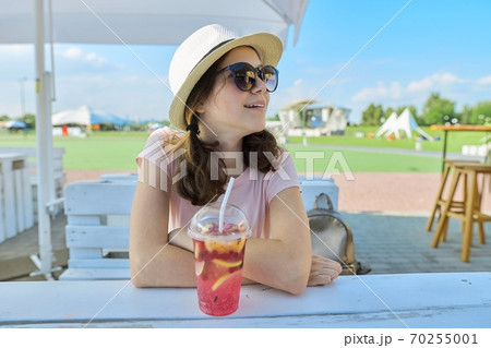 Summer portrait of teenage girl in sunglasses hat with berry cocktail 70255001