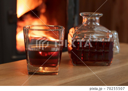 Glass of hard liquor in front of the fireplace. 70255507