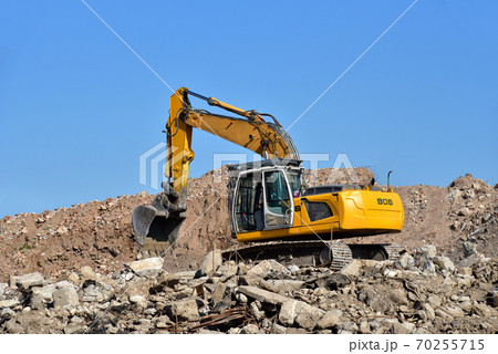 Yellow excavator at landfill for disposal of construction waste. 70255715