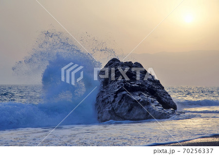 Sea wave beating with force against the rock at sunset Sea wave beating with force against the rock at sunset 70256337