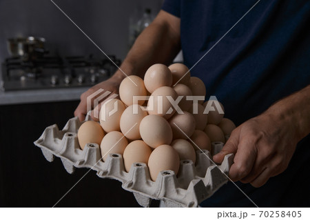 a man holding a full tray of chicken eggs in his own kitchen 70258405