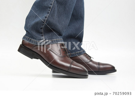Male legs in jeans and brown classic shoes on white background 70259093