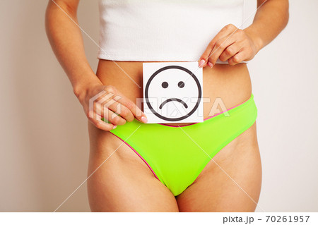 Women's health, women's body holds a card of a sad smile near the belly Women's health, women's body holds a card of a sad smile near the belly 70261957