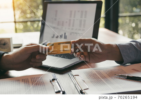 The bank clerk is talking to a customer who applied for a credit card service at the office. The bank clerk is talking to a customer who applied for a credit card service at the office. 70265194