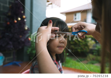 Mom was cutting her hair for her daughter at home. Mom was cutting her hair for her daughter at home. 70265238