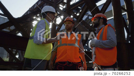 Inspector speaking with builders on construction site 70266252