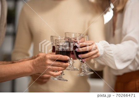 Hands of four family members in casualwear clinking with glasses of red wine Hands of four family members in casualwear clinking with glasses of red wine 70266471