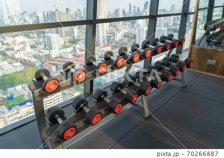 Dumbbells weights in Modern fitness center club with gym equipment decoration in sport or recreation concept. Working out. Interior design background with Bangkok City view, Thailand. 70266887