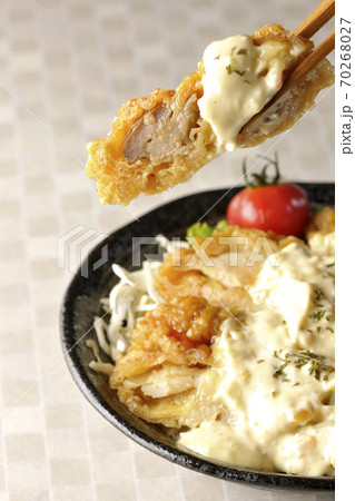 ミニトマトなど野菜も一緒に乗っているタルタルソースたっぷりのチキン南蛮丼の一切れを箸でつまんで食べる ミニトマトなど野菜も一緒に乗っているタルタルソースたっぷりのチキン南蛮丼の一切れを箸でつまんで食べる 70268027