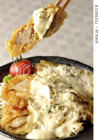 ミニトマトなど野菜も一緒に乗っているタルタルソースたっぷりのチキン南蛮丼の一切れを箸でつまんで食べる ミニトマトなど野菜も一緒に乗っているタルタルソースたっぷりのチキン南蛮丼の一切れを箸でつまんで食べる 70268028