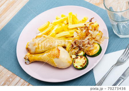 Baked chicken legs with potatoes and zucchini at plate Baked chicken legs with potatoes and zucchini at plate 70273436