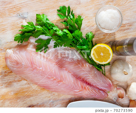 Perch fillet on cutting board with lemon and parsley. 70273590