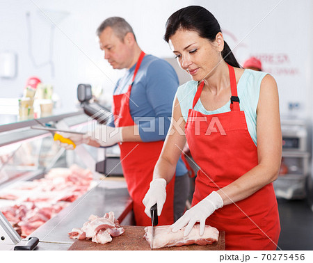 Two seller working in shop, woman cutting meat 70275456