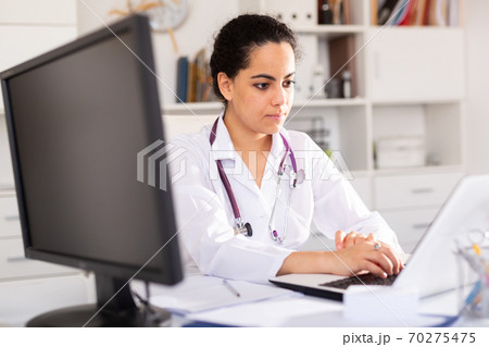 Female doctor working on laptop in office Female doctor working on laptop in office 70275475