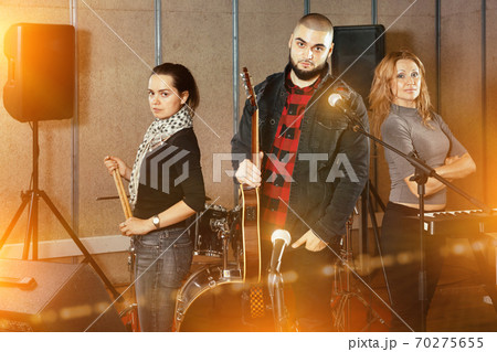 Three bandmates posing together with musical instruments in rehe Three bandmates posing together with musical instruments in rehe 70275655