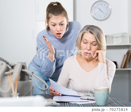 Sad young female and mother with financial documents 70275814