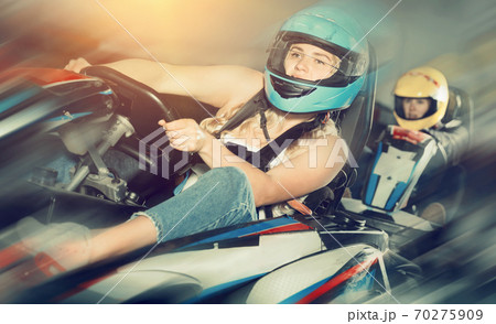 Female racer in helmet driving kart on track 70275909