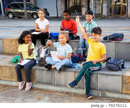 Schoolchildren with hands raised during lesson outside school 70276111