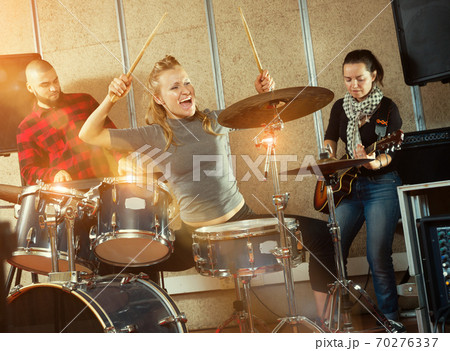 Music band with jolly girl drummer rehearsing Music band with jolly girl drummer rehearsing 70276337