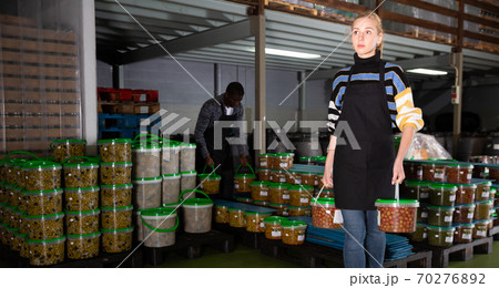 Workers store plastic containers with ripe olives in factory 70276892