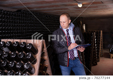 Winemaker with clipboard in wine cellar 70277144