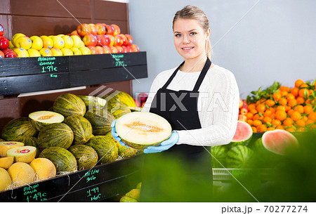 Greengrocery salesgirl offering melon Greengrocery salesgirl offering melon 70277274
