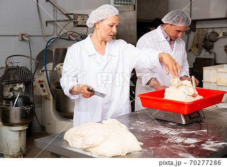 Female baker portioning dough Female baker portioning dough 70277286