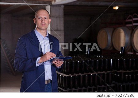 Winemaker with clipboard in wine cellar Winemaker with clipboard in wine cellar 70277536
