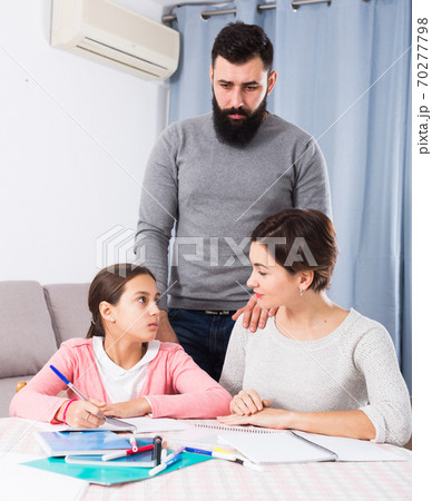 Parents helping daughter with homework 70277798