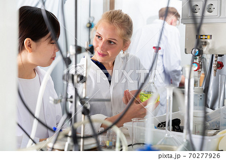 Woman lab technician with female assistant working with reagents Woman lab technician with female assistant working with reagents 70277926