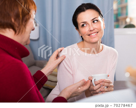 Women sitting together with cup of tea at sofa Women sitting together with cup of tea at sofa 70278467