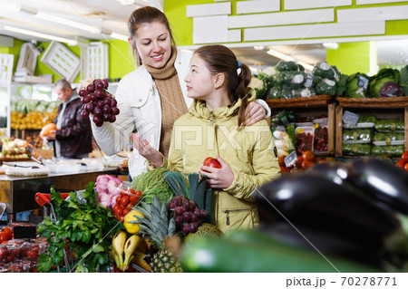 Preteen girl with young woman looking for fresh delicious fruits 70278771