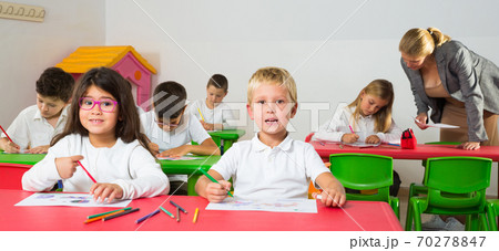 Cheerful school kids studying in classroom Cheerful school kids studying in classroom 70278847