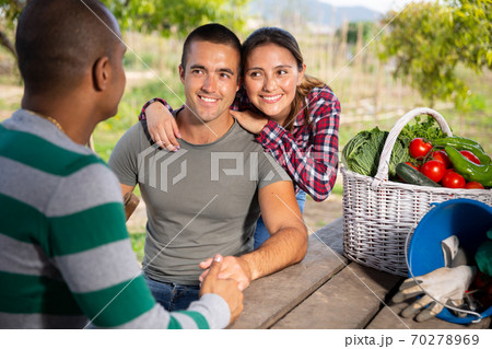 Cheerful couple of gardeners talking to neighbor outdoors Cheerful couple of gardeners talking to neighbor outdoors 70278969