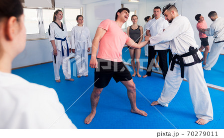 Coach explaining painful hold in taekwondo class 70279011