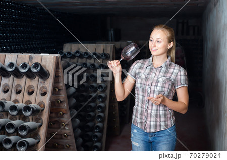 Happy woman holding glass of wine in cellar 70279024