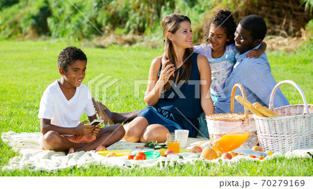 Boy playing on smartphone during family picnic Boy playing on smartphone during family picnic 70279169