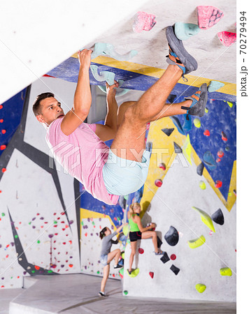 Male alpinist practicing indoor rock-climbing on artificial boulder without safety belts 70279494