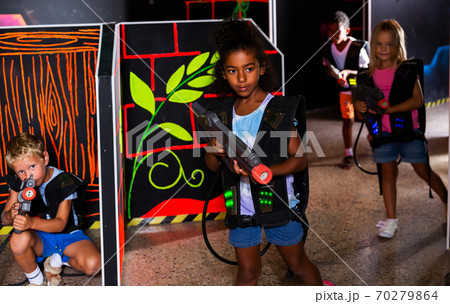 Teenager girl with laser pistol posing in laser tag labyrinth Teenager girl with laser pistol posing in laser tag labyrinth 70279864